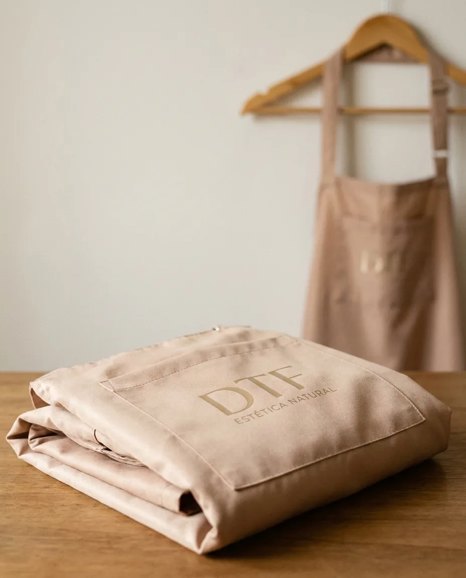 Mandil impermeable rosa nude con logo dorado aplicado con DTF para centro de estética premium